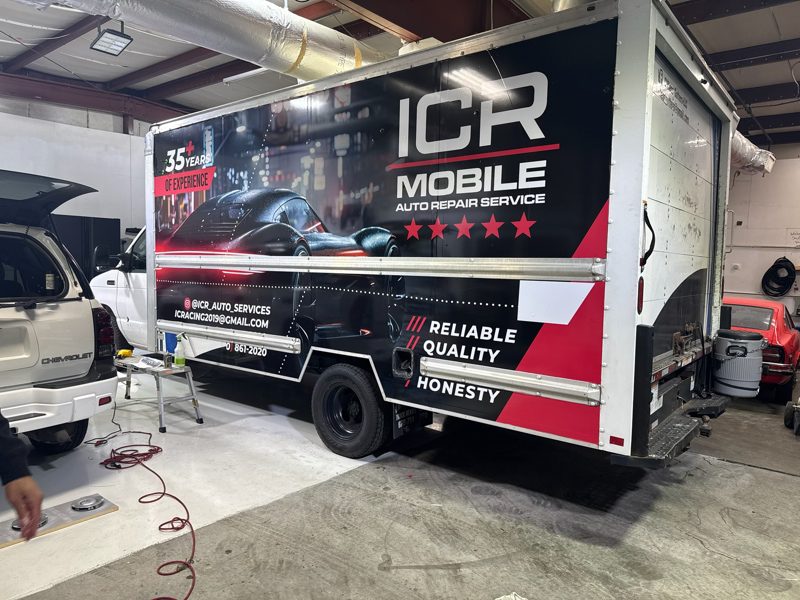 ICR Mobile Auto Repair Service trailer inside a workshop, with tools and cars around it.