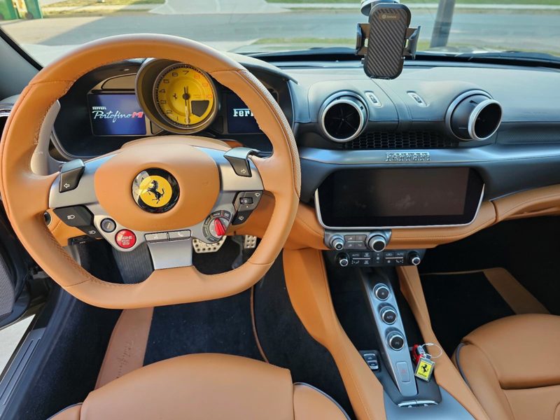 Tan Ferrari interior with a yellow tachometer centered on the steering wheel, and tan leather seats and console.