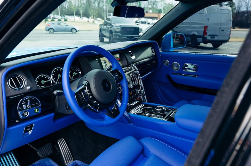 Luxurious blue leather car interior with a prominent blue steering wheel and glossy dashboard controls.
