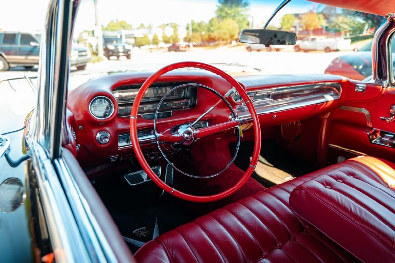 Red vintage car interior with a large circular red steering wheel and red leather seats.